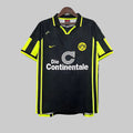 Black sports jersey with yellow accents on a hanger against a geometric patterned background