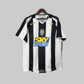 A Juventus soccer jersey from the 2004/05 season, predominantly black with white and yellow details, hanging on display.